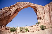 A girl mimics Corona Arch near Moab, Utah