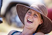 A woman laughs while wearing a sunhat on the shore of Bear Lake.