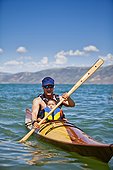 A man paddles a wooden kayak with a 3 year old boy sitting on his lap, Bear Lake.
