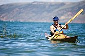A man paddles a wooden kayak with a 3 year old boy sitting on his lap, Bear Lake.
