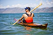 A man paddles a wooden kayak in Bear Lake, Utah.