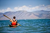 A man paddles a wooden kayak in Bear Lake, Utah.