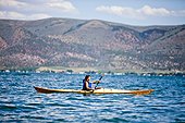 A Japanese-American woman in her thirties paddles a wooden kayak, Bear Lake.