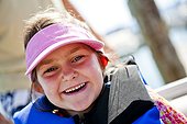 A five year old girl smiles while wearing a pink visor and a life jacket, Bear Lake, Utah.