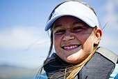 A middle school aged girl, smiles as her wind whips across her face while wearing a blue visor, Bear Lake Utah.