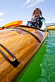 A woman sits in the wooden kayak with sea turtles as it is attached to the back of the pontoon boat in the middle of Bear Lake.