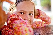 An eight year old girl looks into the camera while sitting at a red picnic table, Garden City, Utah.