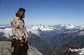 A climber stands triumphantly on Mt. Albert with the British Columbia coast range extending into the distance.