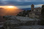 Sunrise over a rocky ledge and stone church in Margalef, Spain