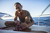 Man cutting slices of tuna fish on sailboat, Mallorca, Spain