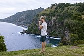 Adult man standing on edge of coastal cliff and brushing teeth, Bali, Indonesia