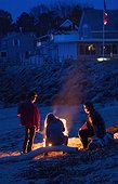 Friends gathered around campfire at beach, Biddeford, Maine, USA