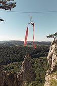 Female aerial silk gymnast performing over forested landscape 30 meters above ground, Lower Austria, Austria