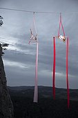 Two female aerial silk gymnasts performing against cloudy sky 30 meters above ground at dusk, Lower Austria, Austria