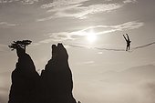 Silhouette of man doing handstand on highline against sun and over foggy hills, Lower Austria, Austria