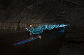 Man paddleboarding and light painting in underground river, Vienna, Austria