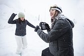Two adult women goofing in snow with wind-up radio, Sandpoint, Idaho, USA