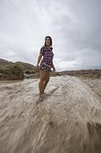 Adult woman standing in middle of dirt road during flash flood in badlands section of Anza Borrego State Park, California, USA