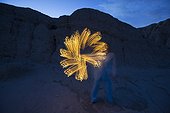 Adult woman creating a flower like shape with a flashlight while she lightpaints at night in the Anza Borrego Desert State Park, California.