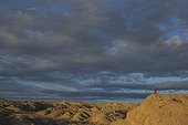 Woman standing atop a desert butte while on a hike at sunrise in the badlands section of Anza Borrego Desert State Park, California.