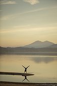 Silhouetted image of an adult woamn doing a handstand along the shoreline of Lake Pend Oreille near Sandpoint, Idaho.