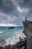 Woman standing on cliff on seashore, Horseshoe Bay, Bermuda