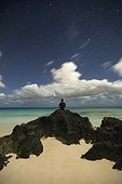 Man sitting on rock at beach and looking at view of ocean, Marley Beach, Bermuda