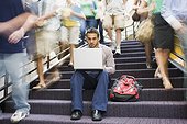 College student using laptop on stairway