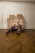 Young couple sitting on floor by packing boxes