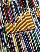 Graph made in pencils among other pens. Still life of yellow pencils forming a graph lying among an assortment of other pens and pencils