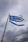 shredded Greek flag. shredded Greek flag blowing in a strong wind on a rusty flagpole