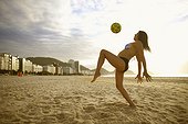 Girl kneeing ball on beach