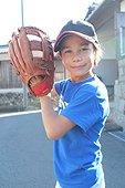 Young boy holding a baseball glove and posing in the street wearing a cap