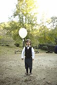 Young boy holding a white balloon outside