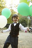 Young boy holding colorful party balloons outside