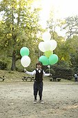Young boy holding colorful party balloons outside
