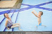 Mother and kid splashing in swimming pool
