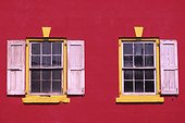 Close-Up of Red House window with vibrant yellow colors and Shutters, Nassau, Bahamas.