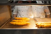 Fried fish in hot cabinet, servers behind