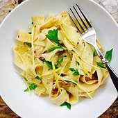 Pappardella pasta lemony carbonara with bacon, flat parsley and lemon garnish