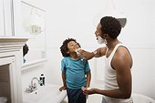 Father applying lather to boy's face