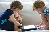 Boy and girl totally involved in an electronic tablet