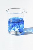 Chemistry lab measuring cup, beaker glass with blue food coloring solution to dissolve