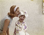 Mother whispering into daughter's ear, smiling