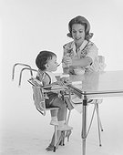 Mother feeding baby on high chair