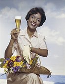 Woman holding flowers basket with beer glass, smiling, portrait