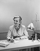 Businesswoman working at desk, smiling, portrait