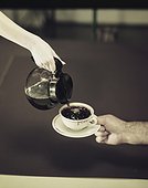 Woman's hand pouring coffee into cup held by man's hand