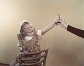 Girl taking ice cream cone from man's hand, smiling