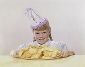 Girl wearing party hat holding wafer tray, smiling, portrait